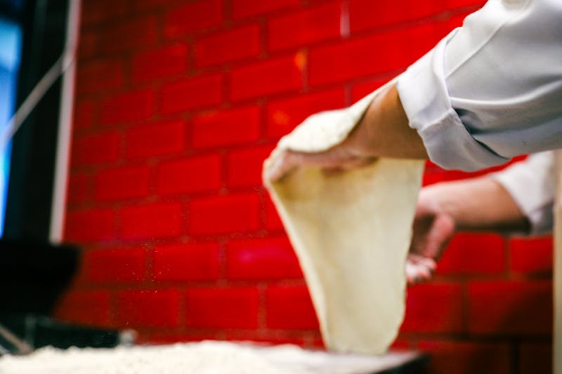 Pizza chef hand-stretching dough in Pequod's kitchen
